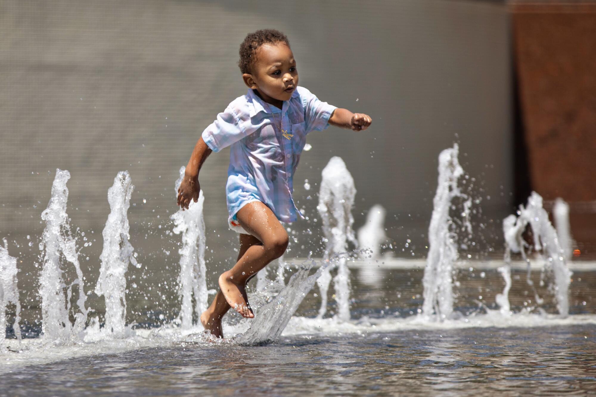 A youngster runs among fountain jets.