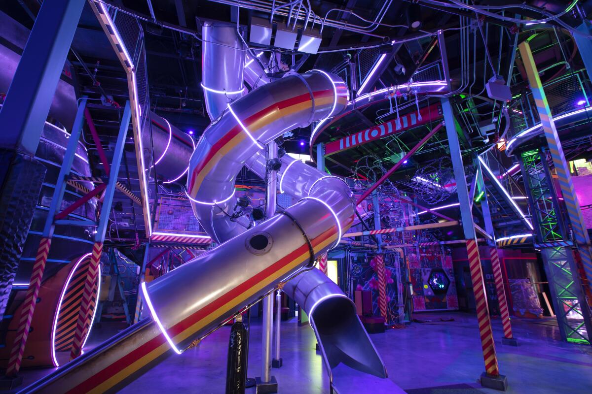 A twisting indoor slide surrounded by neon.