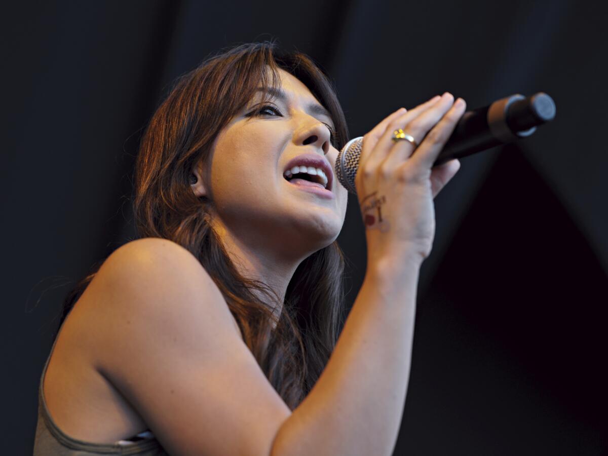 A woman holds a microphone close to her mouth while she sings 