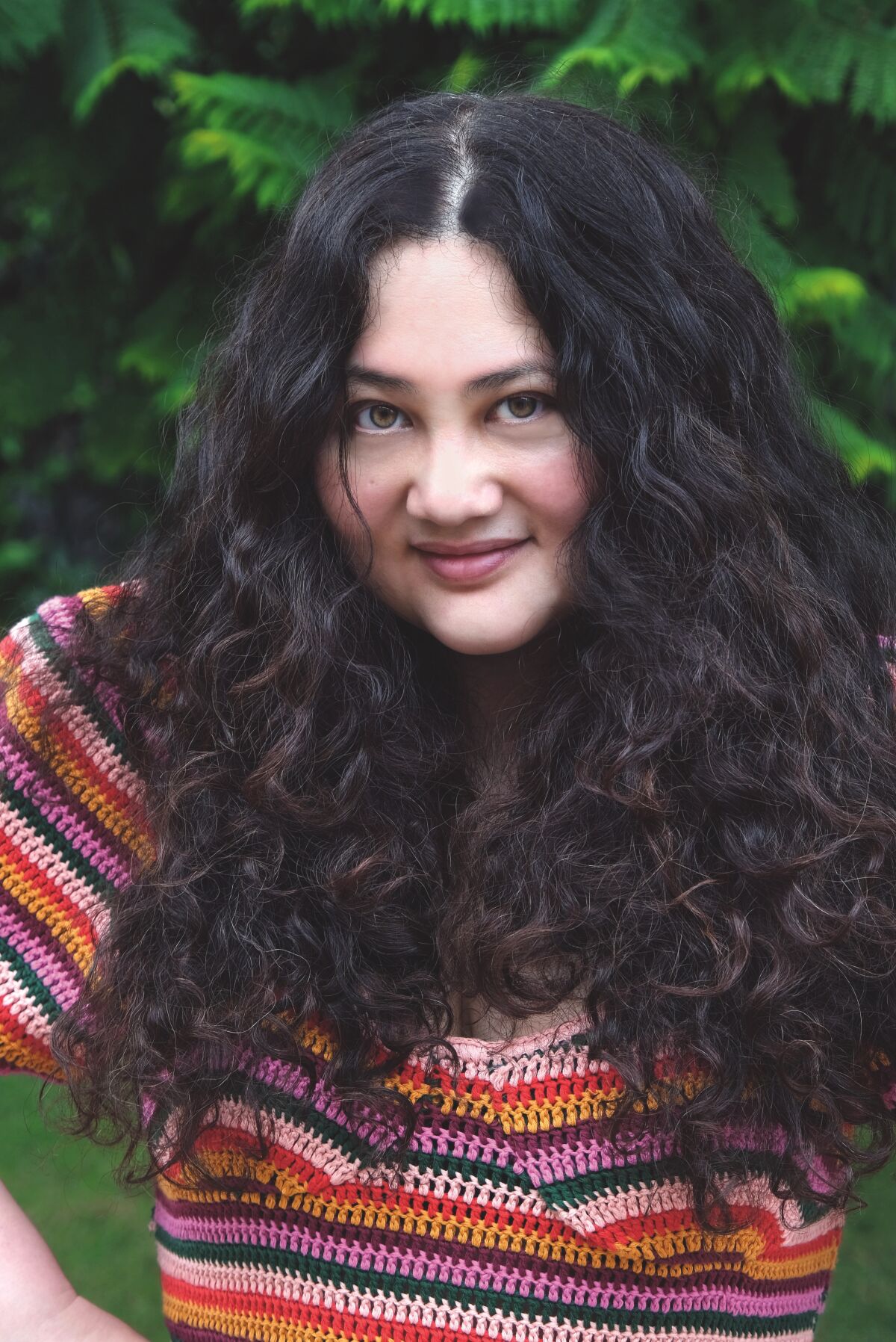 Header image of a woman wearing a colorful striped shirt and bushy black hair