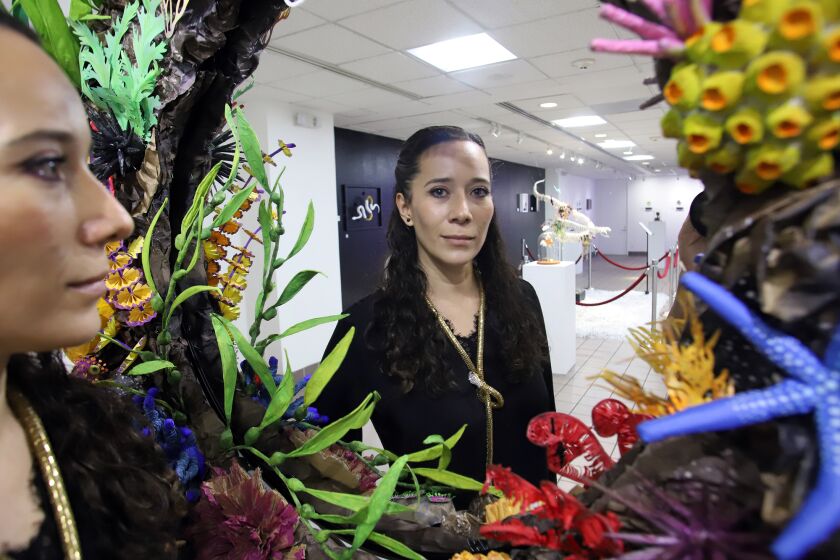 Tania Póo Platas, de 37 años, nacida en la Ciudad de México, se mira a través de un espejo decorado con el arrecife de coral hecho por sus manos. (Foto por James Carbone)