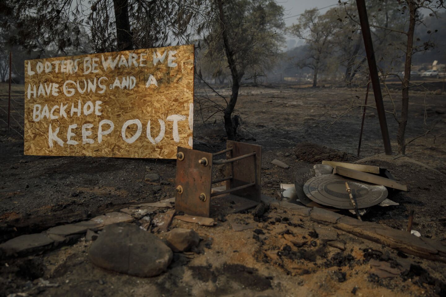 A sign warns looters at the site of burned-down properties in Paradise, Calif.