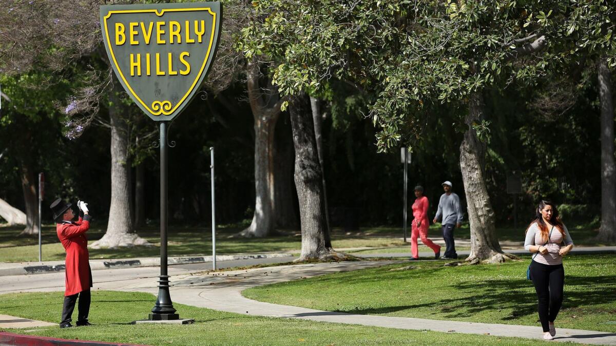 BEVERLY HILLS, CA-APRIL 3, 2014: Gregg Donovan, left, the former "Ambassador of Beverly Hills" takes a photograph of a Beverly Hills sign located at the intersection of Santa Monica Blvd. and Doheny Dr. in Beverly Hills on April 3, 2014. Donovan said that he was taking the photograph at the request of a friend who lives in England. Governor Jerry Brown issued an executive order, mandating that urban consumers statewide cut their water use 25 percent by the end of February, 2016. Under the plan, cities such as Beverly Hills will have to cut water use the most since they are among the state's heaviest per-capita water users. (Mel Melcon/Los Angeles Times)