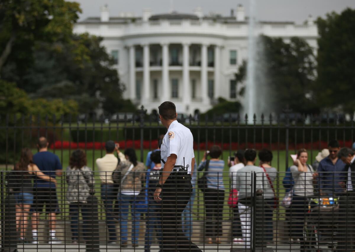 A Secret Service member watches as tourists visit the White House on Sept. 30, 2014. On Tuesday, Army Veteran Omar Gonzalez was sentenced to 17 months for his White House intrusion.