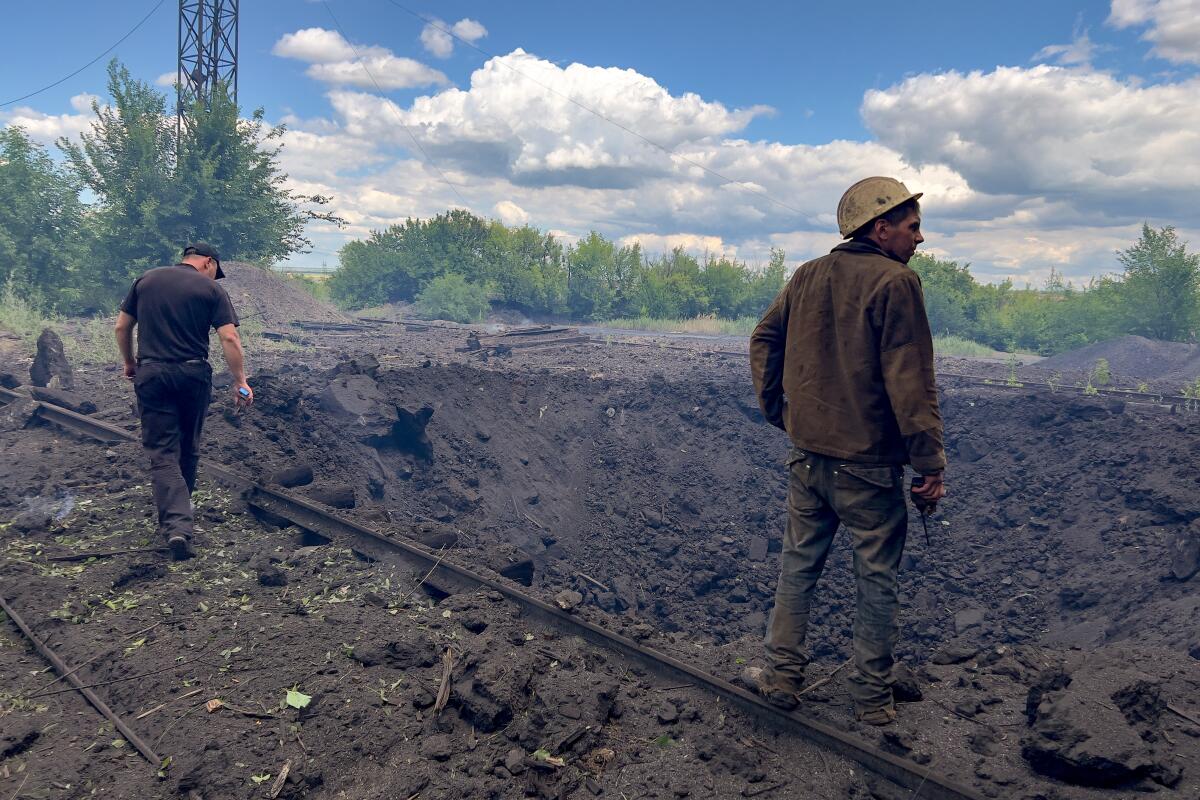 Two men stand near the edge of a crater 