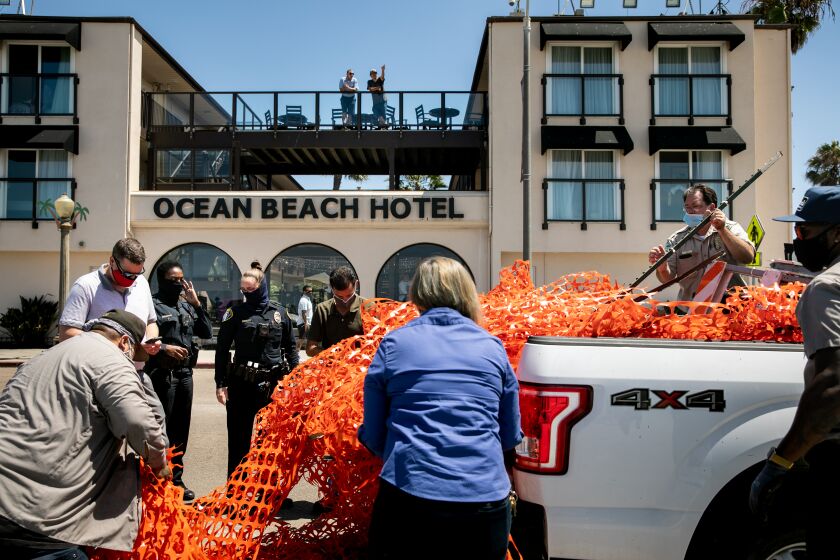 SAN DIEGO, CA - AUGUST 11: Two San Diego Police Department officers showed up to investigate as city crews haul away a fence that had been put up to prevent gathering at Ocean Beach Veteran's Plaza and was torn down by unhappy residents on Tuesday, Aug. 11, 2020 in San Diego, CA. The plaza has been the site of large gatherings in recent weeks, with drum circles and fire spinning taking place late into the night with little social distancing. (Sam Hodgson / The San Diego Union-Tribune)