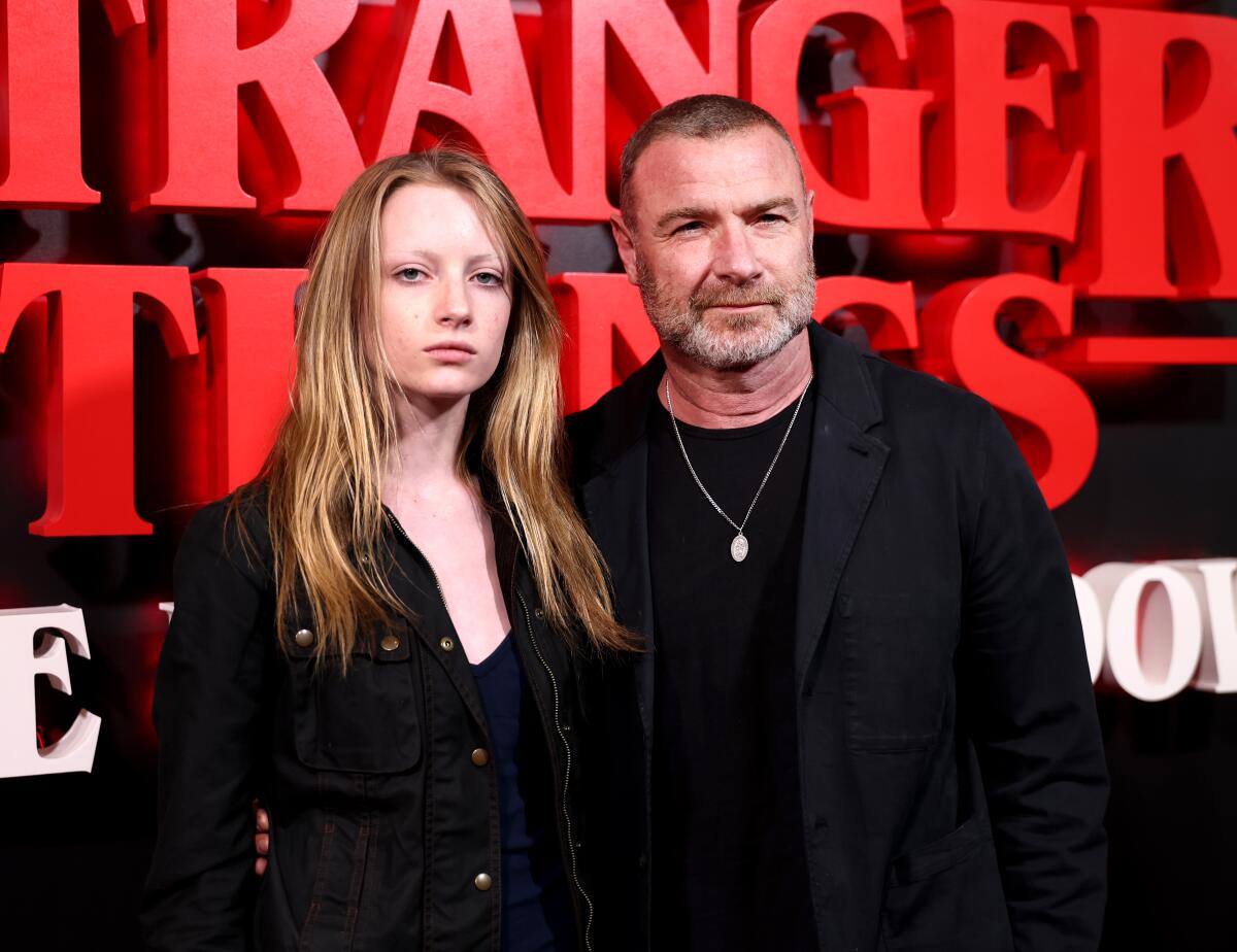 Kai Schreiber and Liev Schreiber wearing black and standing in front of a backdrop