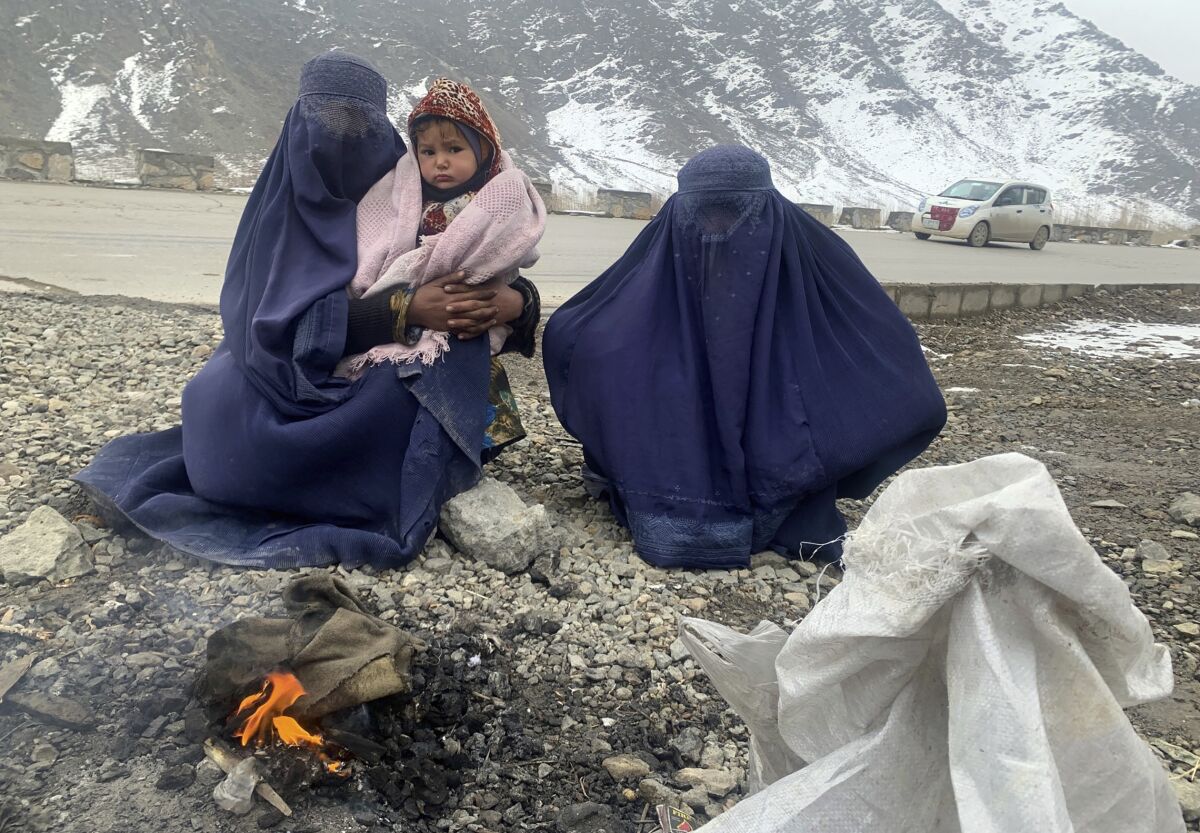 A small group of Afghans struggles to stay warm around a small campfire