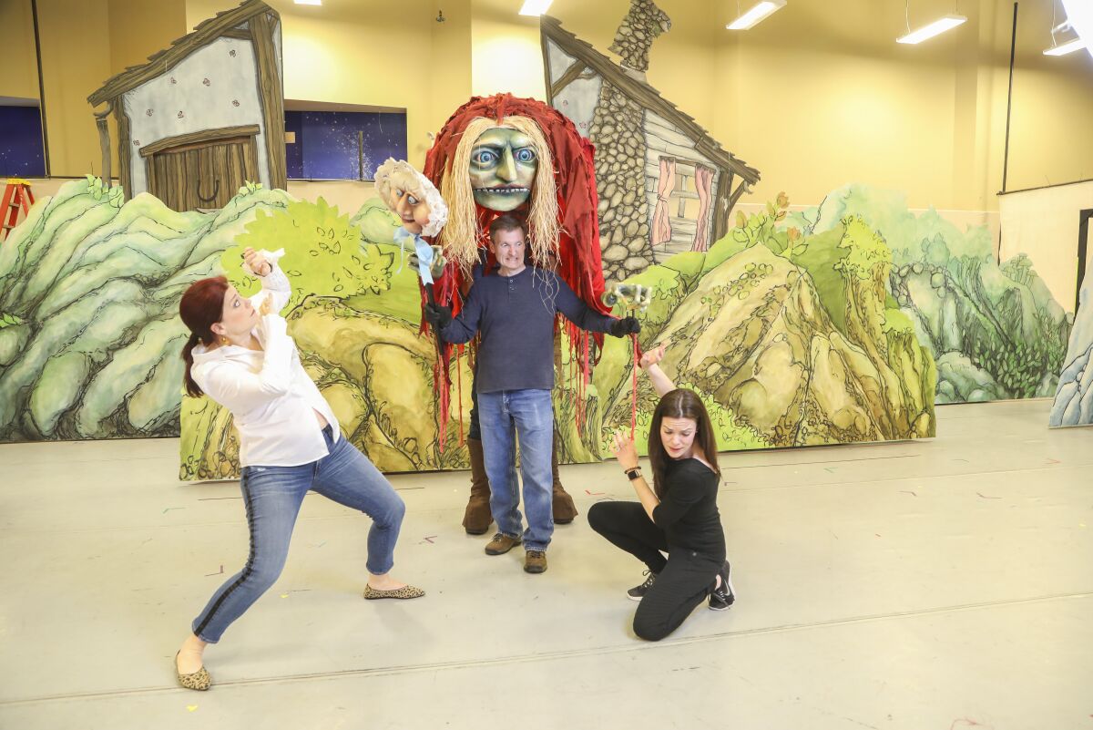 During a rehearsal of San Diego Opera's "Hansel and Gretel" cast members Blythe Gaissert, left, as Hansel, Joel Sorensen as the witch and Sara Gartland as Gretel pose for photos for the production, which will open Feb. 8 at the San Diego Civic Theatre. Not pictured is show designer Judd Palmer, who is operating the back portion of the Witch puppet.