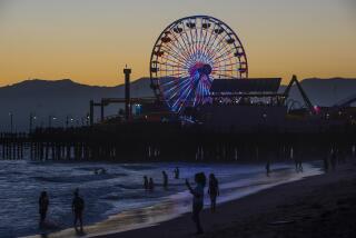 Crowds gather around the Santa Monica Pier's Ferris Wheel as it is lit up for the Independence Day celebrations on July 4, 2021 in Santa Monica. ( Nick Agro / For The Times )