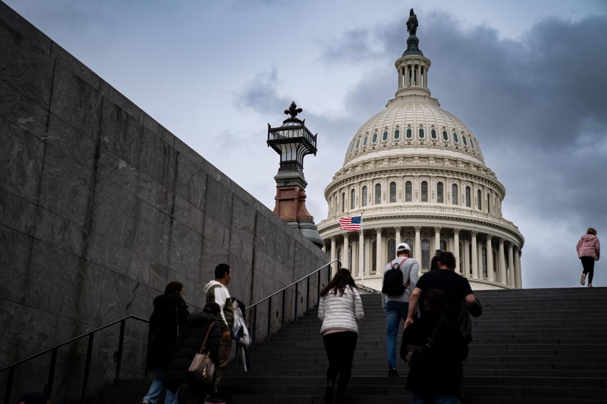Several people walking up an outdoor stairway, with the U.S. Capitol dome in the background