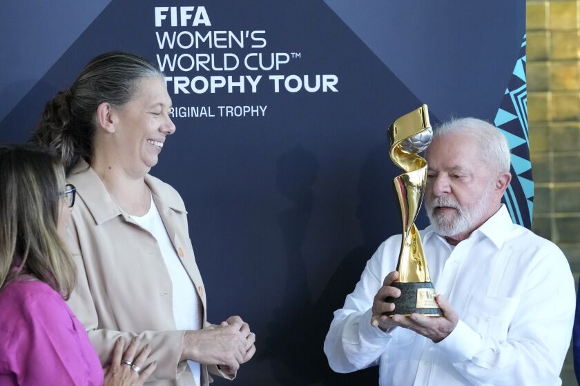 Brazil's President Luiz Inacio Lula da Silva holds the FIFA Women's World Cup Trophy as Minister of Sports Ana Moser looks on during the trophy's tour ahead of the Australia - New Zealand 2023 World Cup soccer tournament at Planalto palace in Brasilia, Brazil, Thursday, March 30, 2023. (AP Photo/Eraldo Peres)