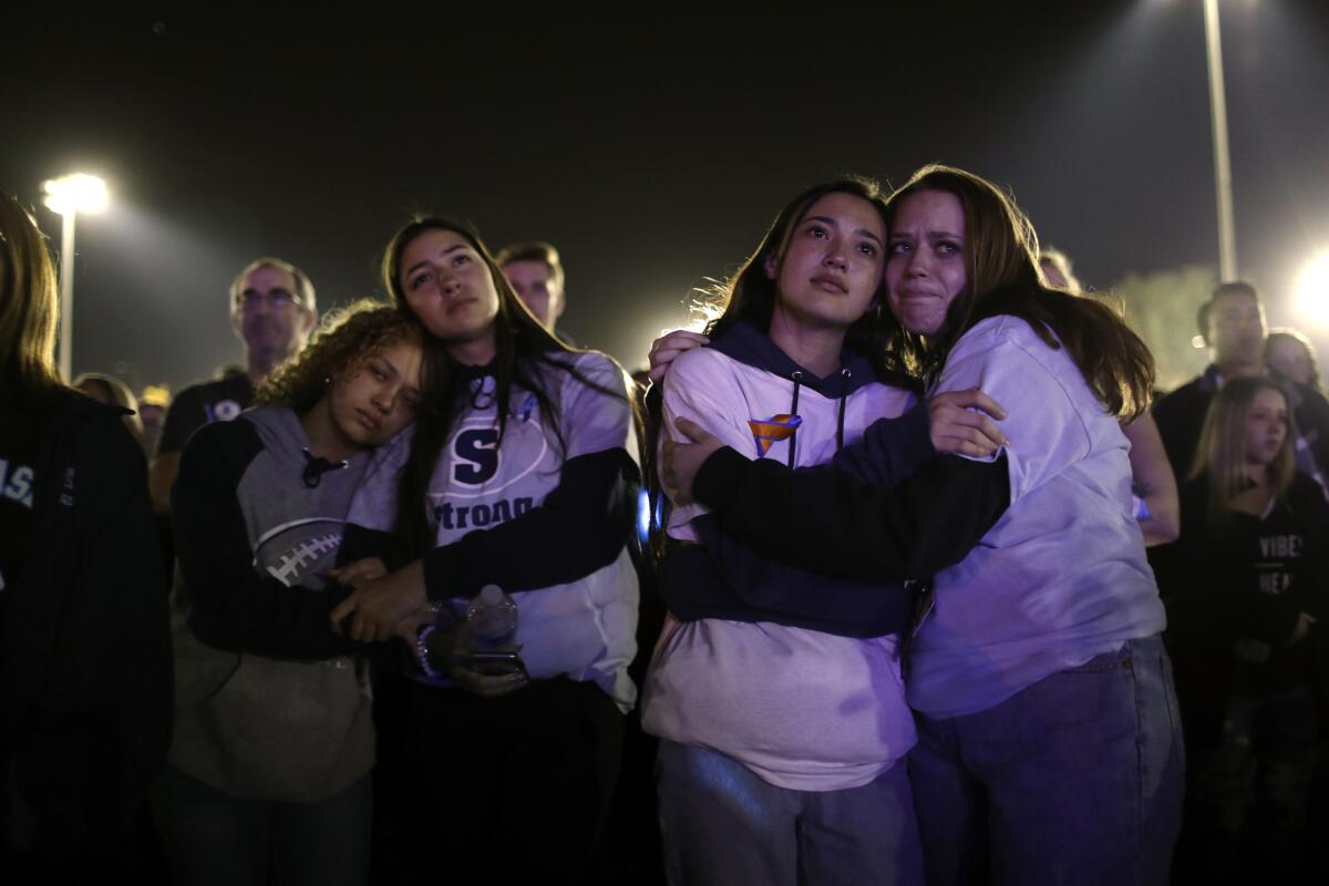 (L-R) Priscilla Arquelles, 17, Kayla Hynes, 16, Gracyn Webb, 17, and Carli Chorpash, 17, hold each other as thousands gather at Central Park in Santa Clarita.