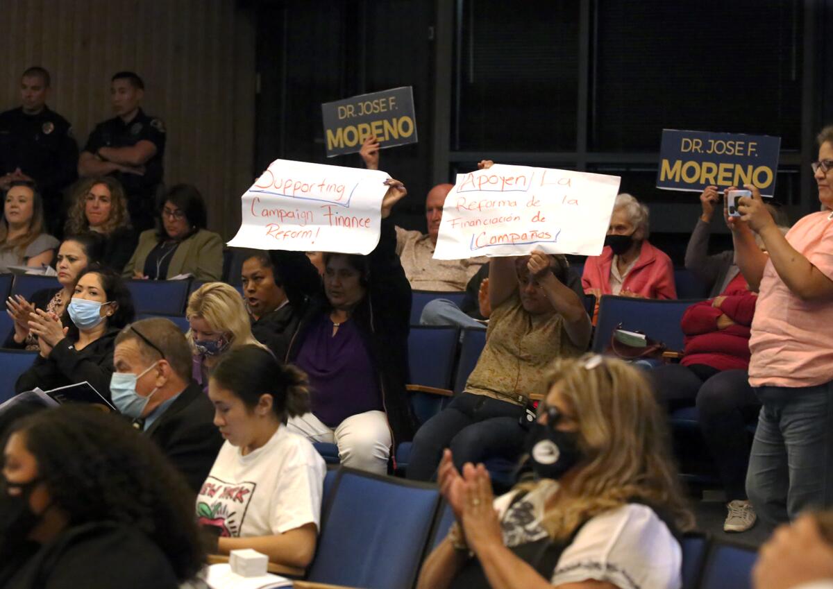 Anaheim residents hold signs in support of campaign finance reform.