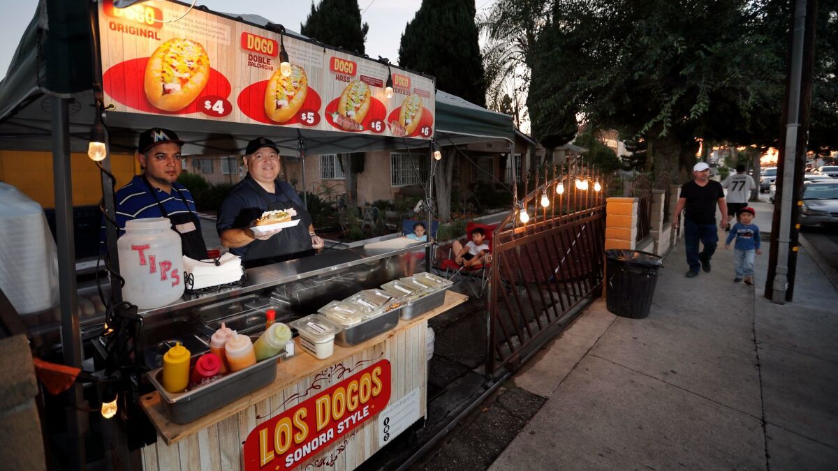 Alejandro Zamorano, right, and his nephew David Zamorano, serve Sonora, Mexico-style hot dogs from their cart in front of a friend's house in Compton.