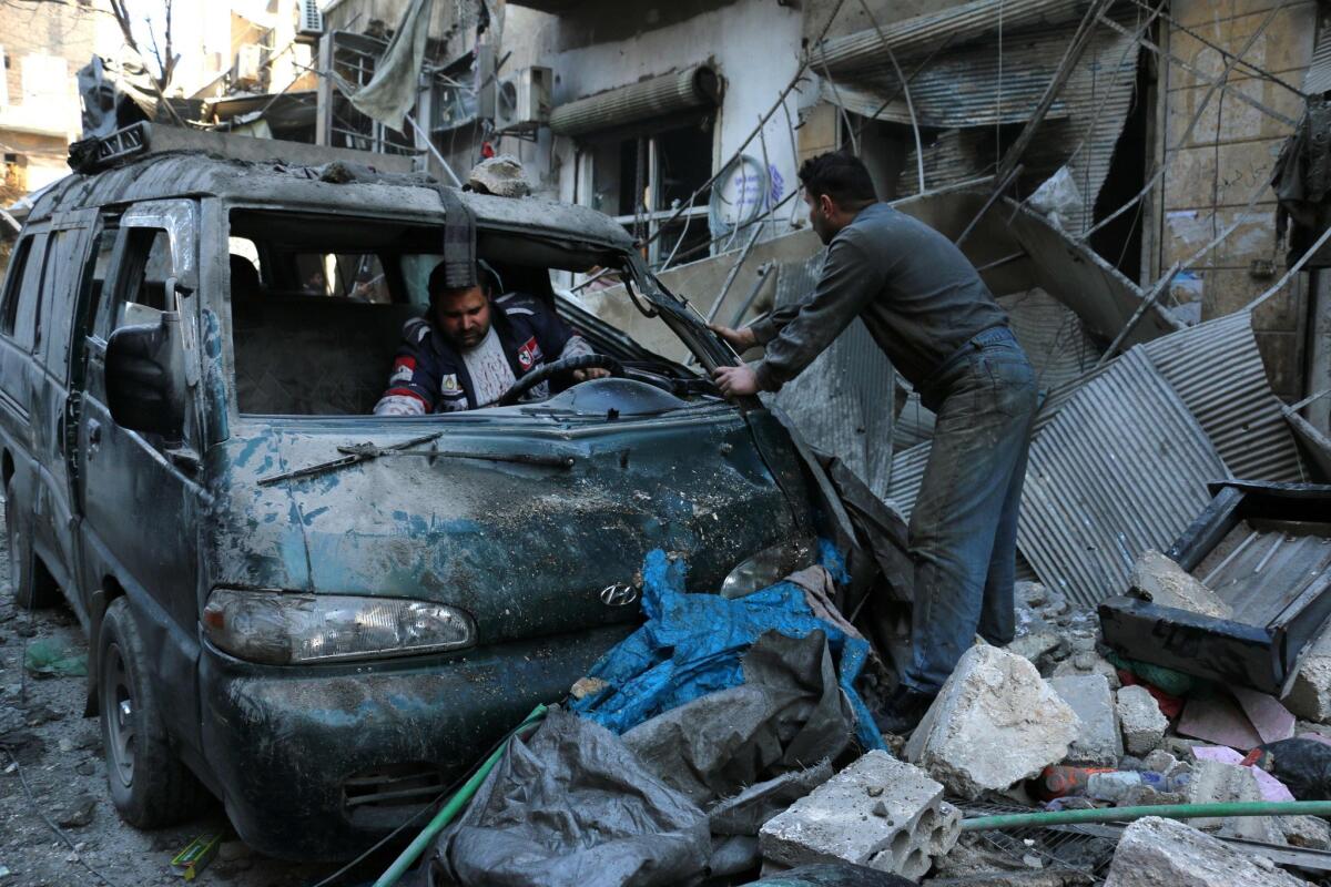 People inspect a damaged vehicle after a reported airstrike by Syrian government forces in the northern city of Aleppo on Saturday. In eastern Syria, Islamic State militants reportedly kidnapped hundreds of civilians.