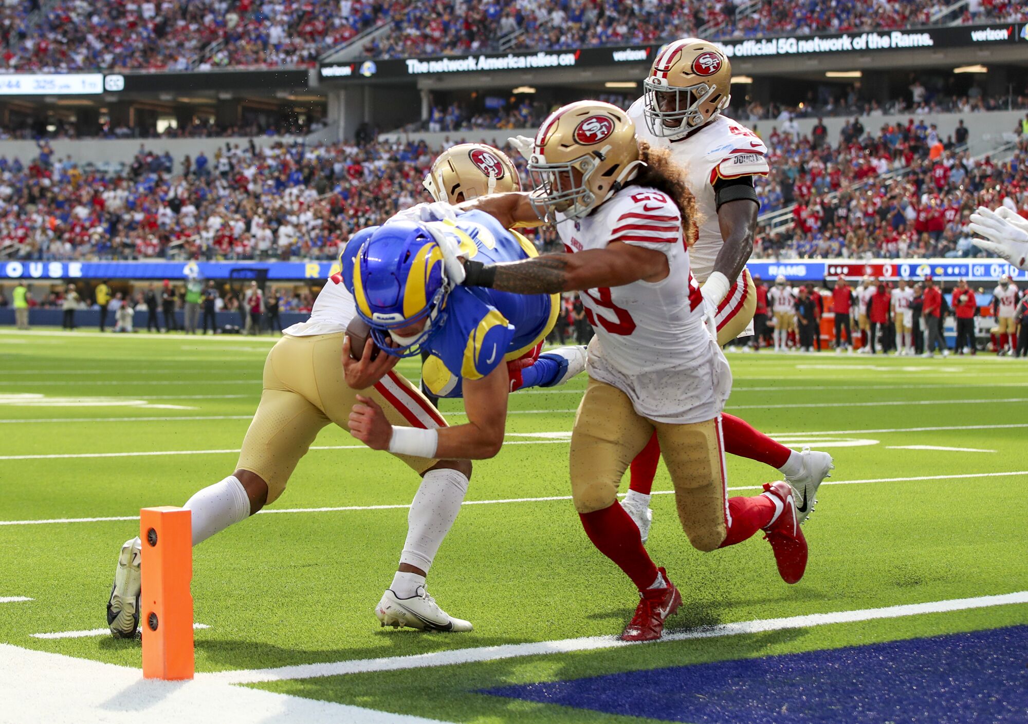 Rams quarterback Matthew Stafford dives into the end zone for a touchdown past 49ers players.