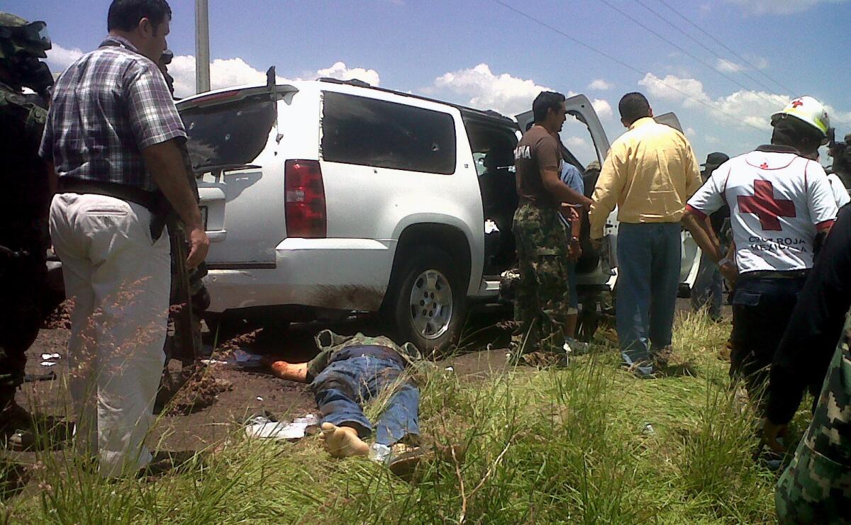 Army and Red Cross personnel stand next to the body of a victim, after a vehicle carrying a Mexican navy vice admiral was attacked by gunmen in Michoacan state.