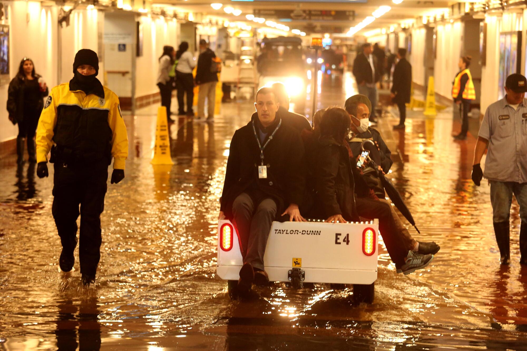 Commuters are shuttled over a flooded section of the pedestrian walkway leading to train platforms 