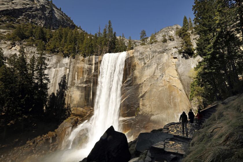 YOSEMITE NATIONAL PARK—APRIL 19, 2021—Hikers navigate the Mist Trail against of backdrop of Vernal Falls in the Yosemite Valley on April 19, 2021. Just in time for the Spring tourism season, Yosemite National Park is open at 50 percent capacity. (Carolyn Cole / Los Angeles Times)