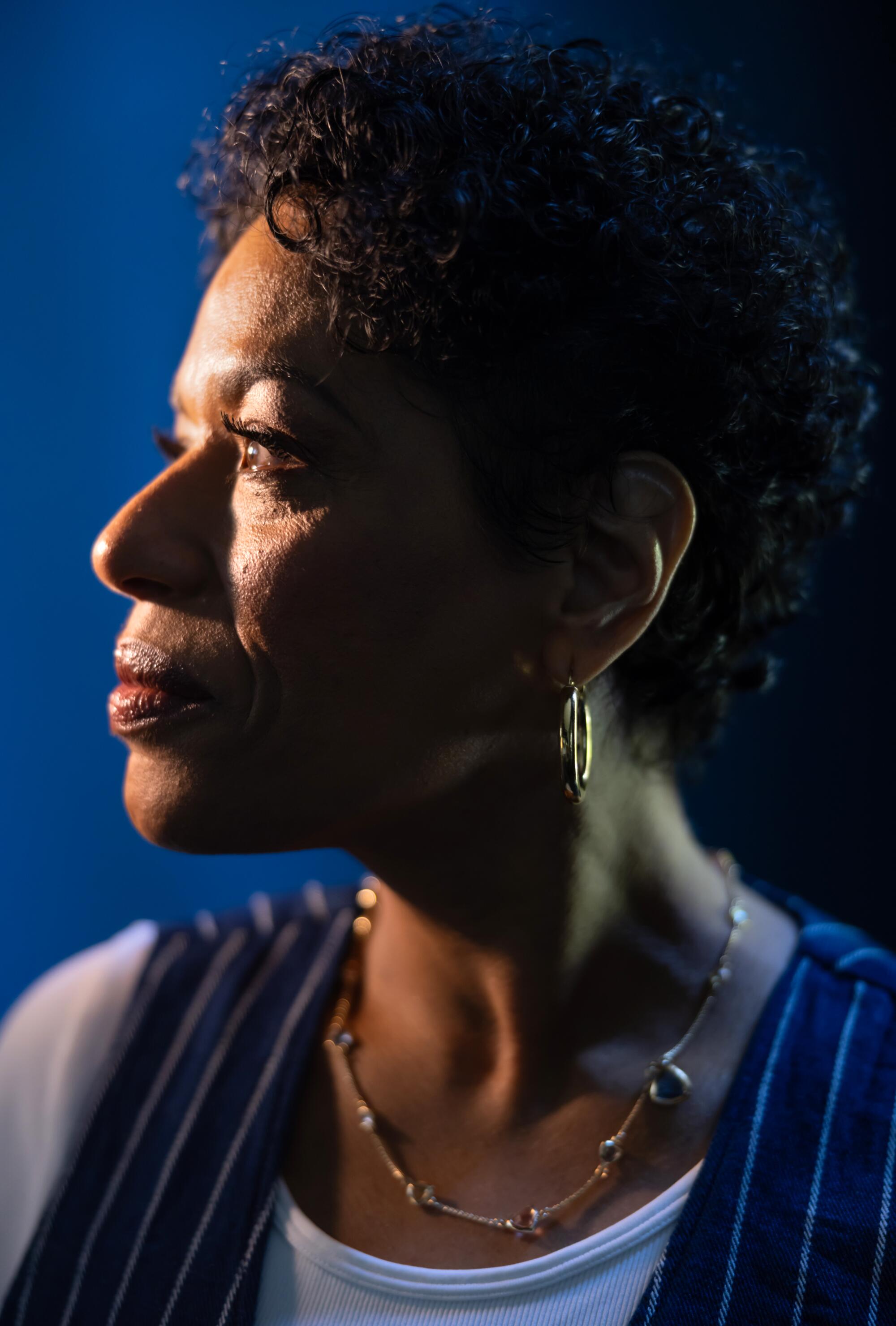 The left side profile of a woman with short, curly brown hair. 