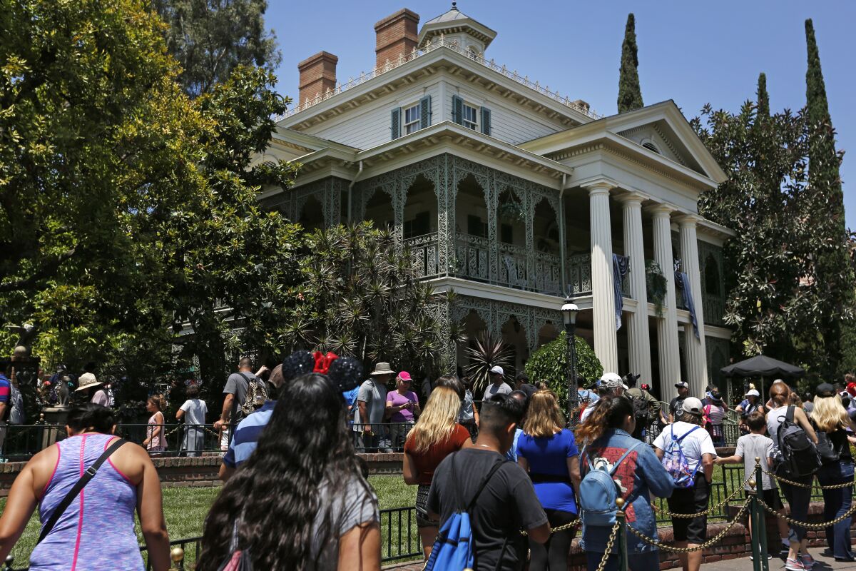 People wait in line outside the Haunted Mansion