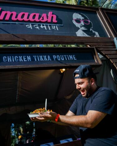 Chef Arjun Mahendro poses with the Chicken Tikka Poutine from Badmaash.