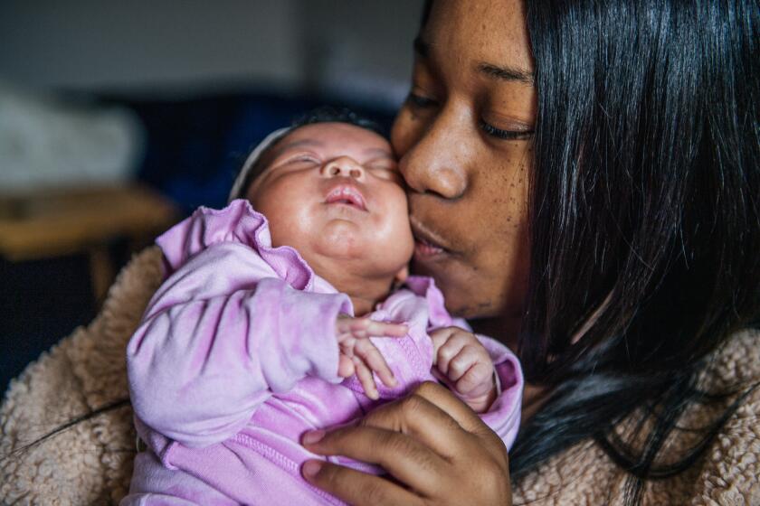 Alexis Small kisses her newborn baby Aubrielle Kitchen during a meeting with family over a Zoom call in Los Angeles