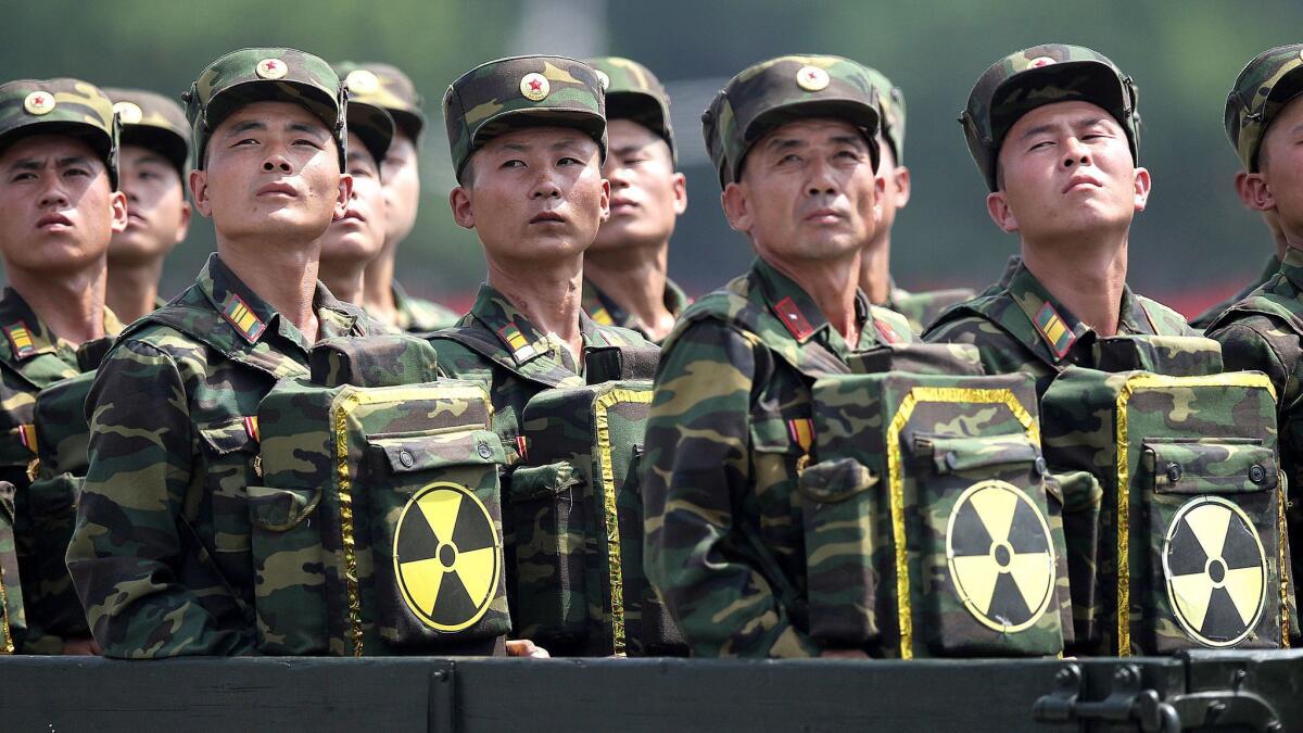 North Korean soldiers carry packs marked with the nuclear symbol look to their leader, Kim Jong Un, from a military parade vehicle in Pyongyang in July 2013.