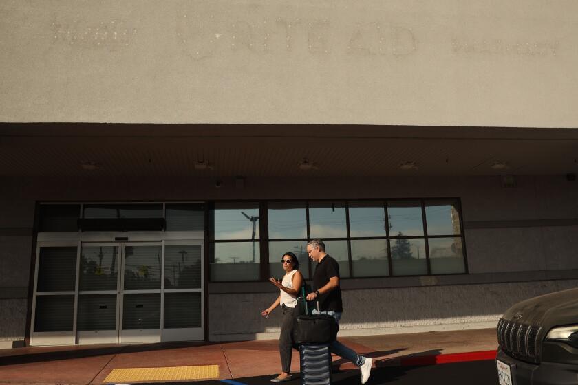 Venice, CA - August 30: A couple walks by a now closed Rite Aid on Lincoln Blvd on Friday, Aug. 30, 2024 in Venice, CA. (Michael Blackshire / Los Angeles Times)