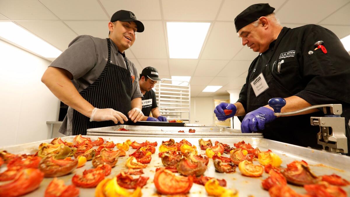 Charlie Negrete, left, works with students Jose Moreno, center, and Michael Hernandez as they prepare to turn oven dried tomatoes into tomato powder.