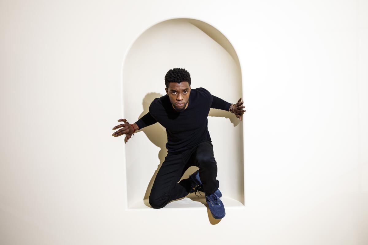 Late actor Chadwick Boseman crouches in the arch of a wall inset