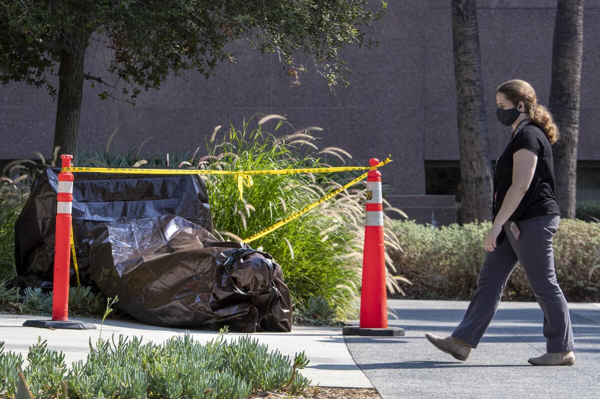 A vandalized statue is wrapped in a brown tarp in Grand Park Friday.