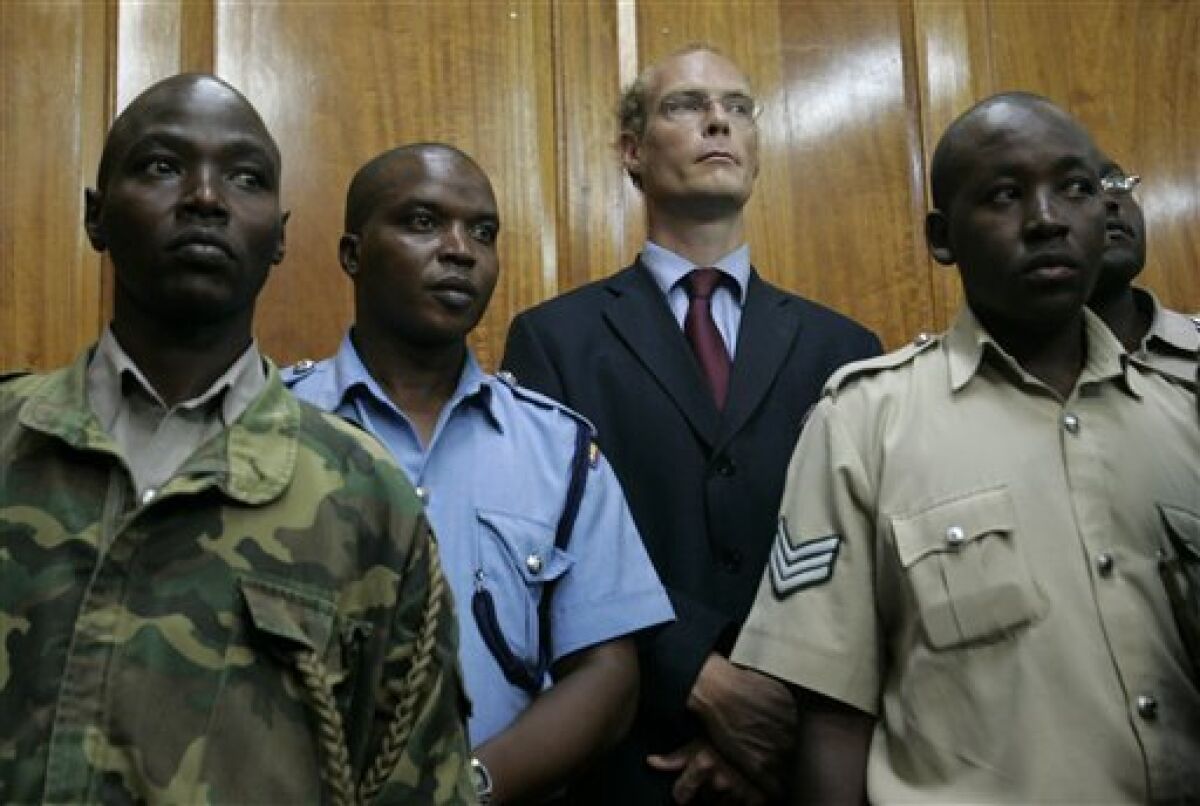 Thomas Cholmondeley, center, stands surrounded by police officers as a judge read the verdict finding him guilty of manslaughter, Thursday, May 7, 2009 in the Nairobi high court, Kenya. A court has convicted a descendant of Kenya's most famous white settlers of manslaughter in the shooting death of a black man on his vast estate, a case that has stirred simmering tensions over race and land in Kenya.Thomas Cholmondeley, 40, wearing a blue suit and red tie, looked down when the verdict was read; some of his family and friends started crying.(AP Photo/Karel Prinsloo)