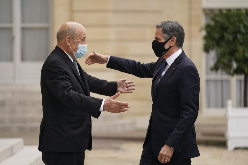 Secretary of State Antony Blinken and French Foreign Affairs Minister Jean-Yves Le Drian move to embrace at Elysee Palace.