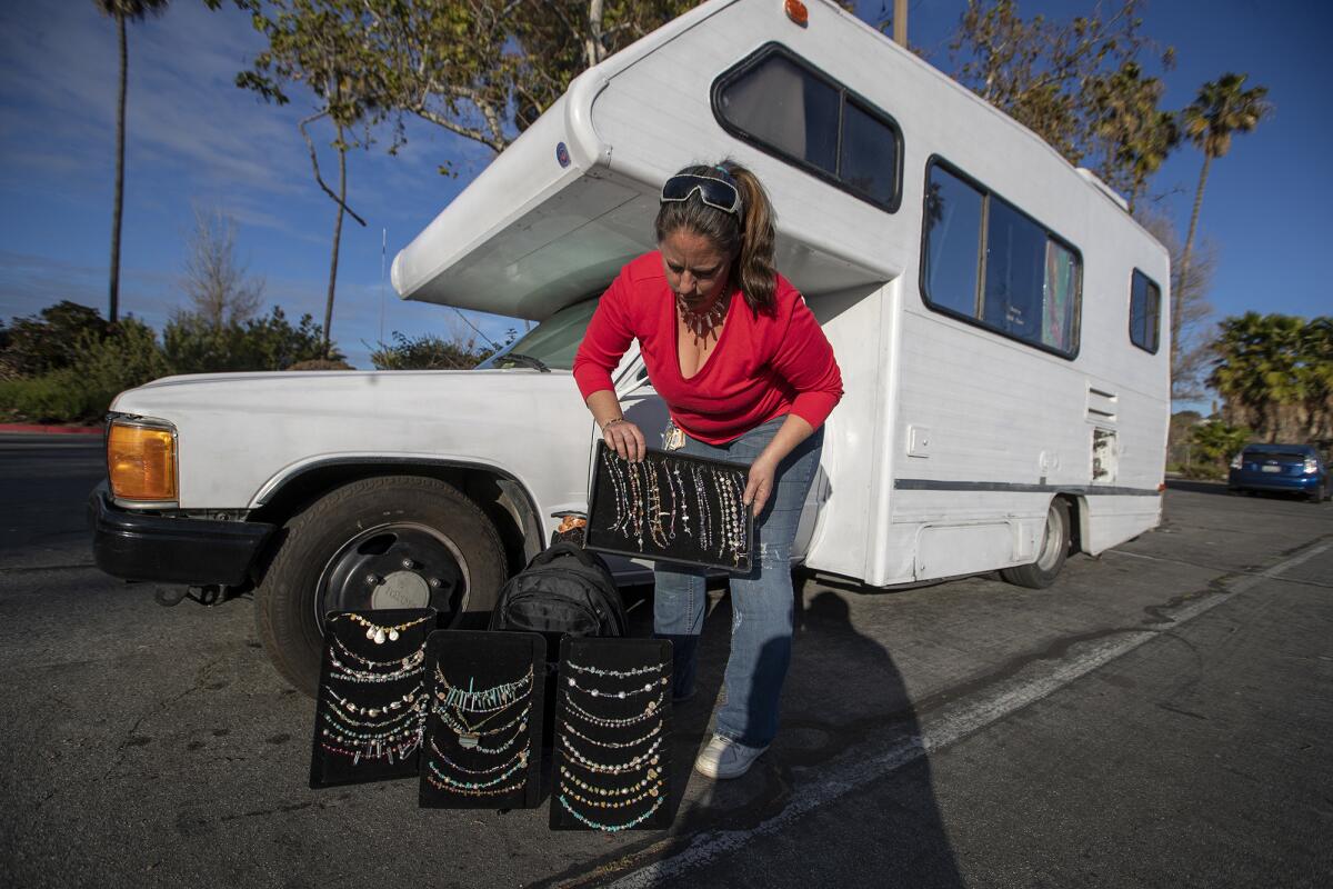 Mandy Pittock, who lives with her guinea pig in a motor home, shows off jewelry she makes before she lines up for a meal at the beach.