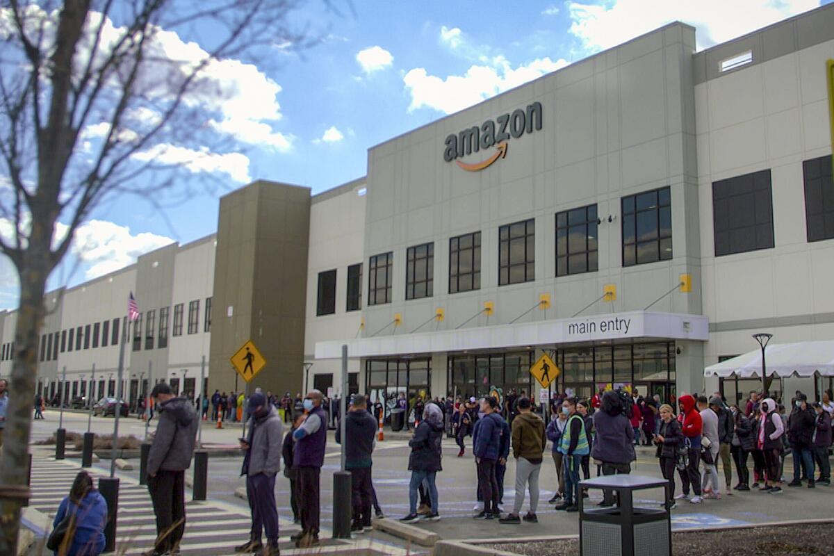 FILE - In this image from video, Amazon workers line up outside the company's facility, in Staten Island borough of New York, March 25, 2022. Amazon has suspended at least 50 workers who refused to work their shifts following a trash compactor fire at the warehouse, Tuesday, Oct. 4, 2022, according to union organizers. (AP Photo/Robert Bumsted, File)