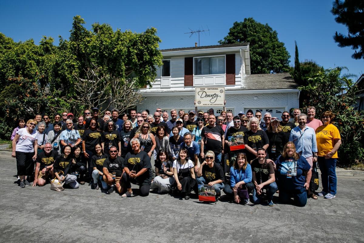 Carpenters fans pose for a group photo in front of the band's original home, in Downey, part of a tour offered by the Carpenters convention.