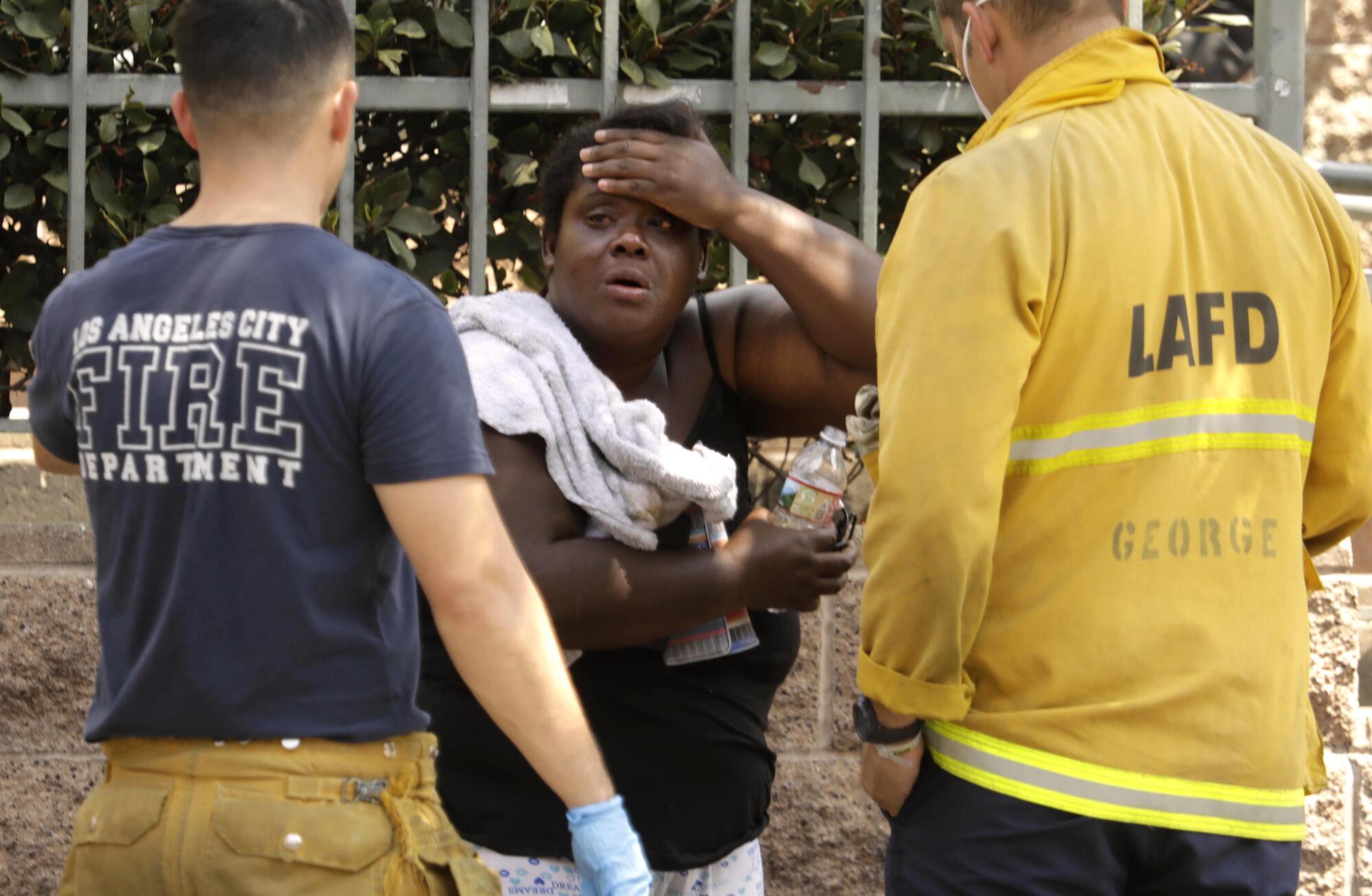 Firefighters treat a homeless woman gasping for air in front of the L.A. Mission along 5th Street on skid row.