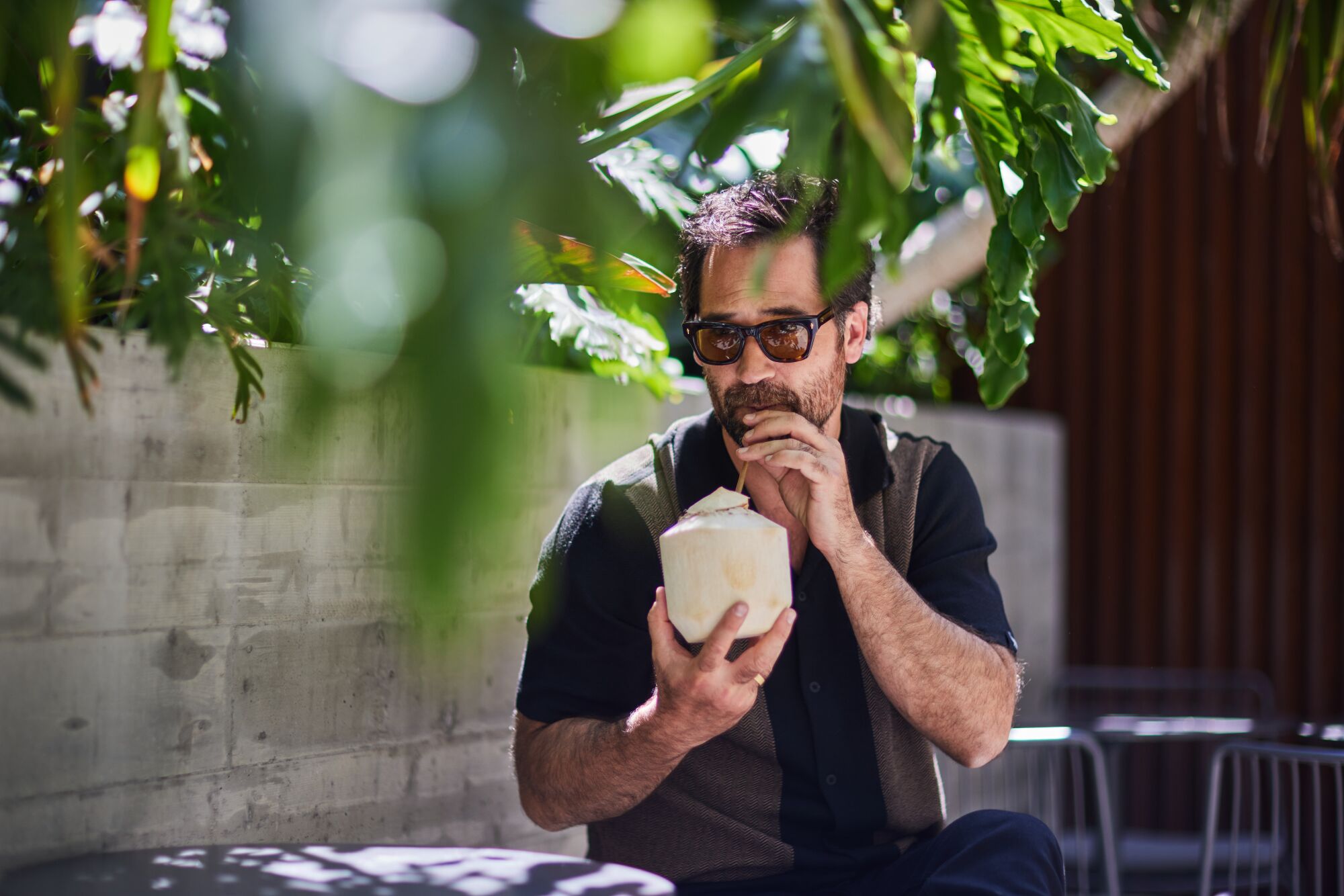 Manuel Garcia-Rulfo, wearing sunglasses, sips from a coconut with a straw.