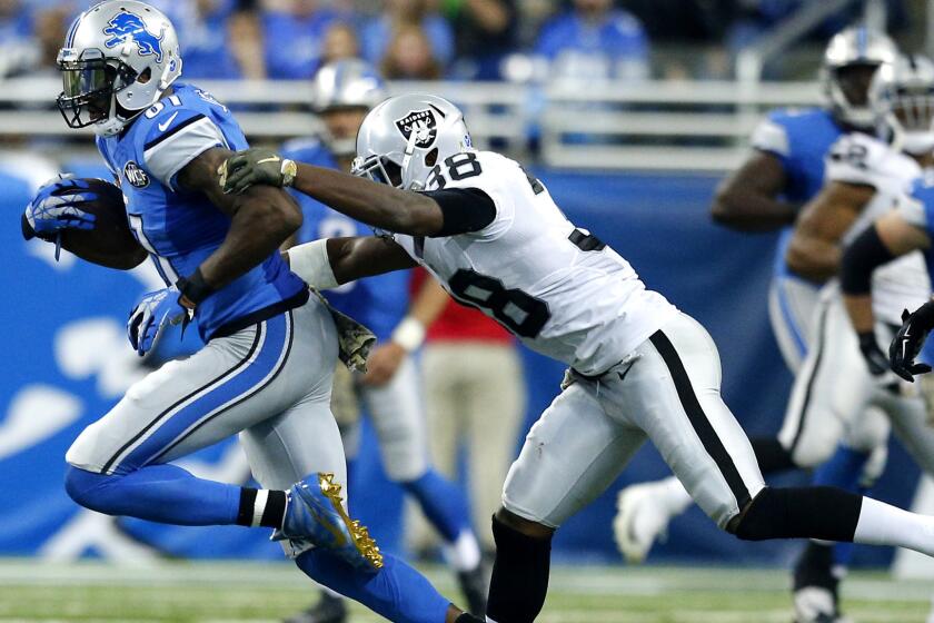 Raiders safety T.J. Carrie tries to tackle Lions wide receiver Calvin Johnson after a reception in the first half Sunday.