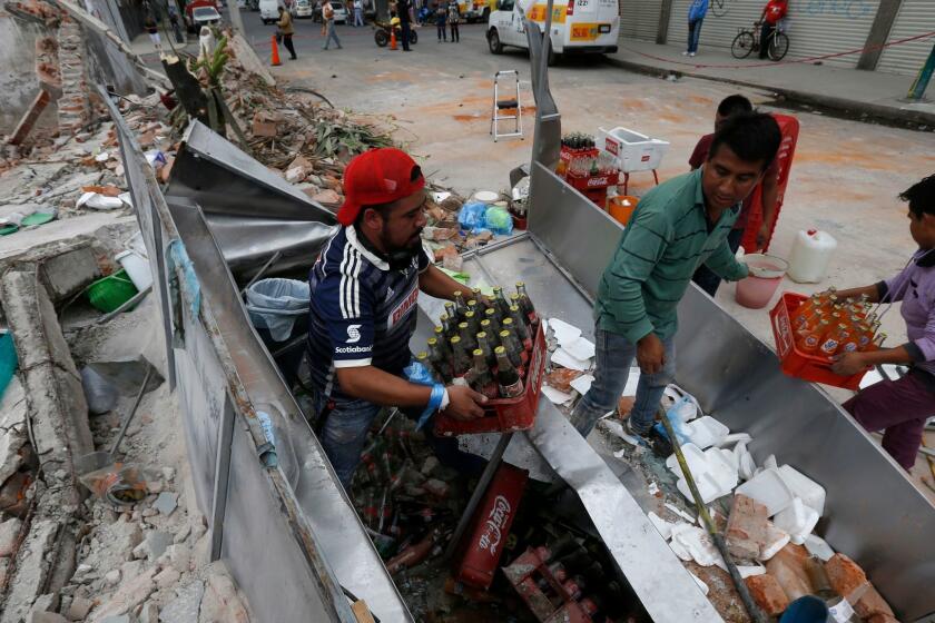 Residents remove sodas from the fridge of their taco stand after a wall collapsed on it during the earthquake in Mexico City, Friday, Sept. 8, 2017. One of the most powerful earthquakes ever to strike Mexico hit off its southern Pacific coast, while the capital escaped major damage. (AP Photo/Marco Ugarte)