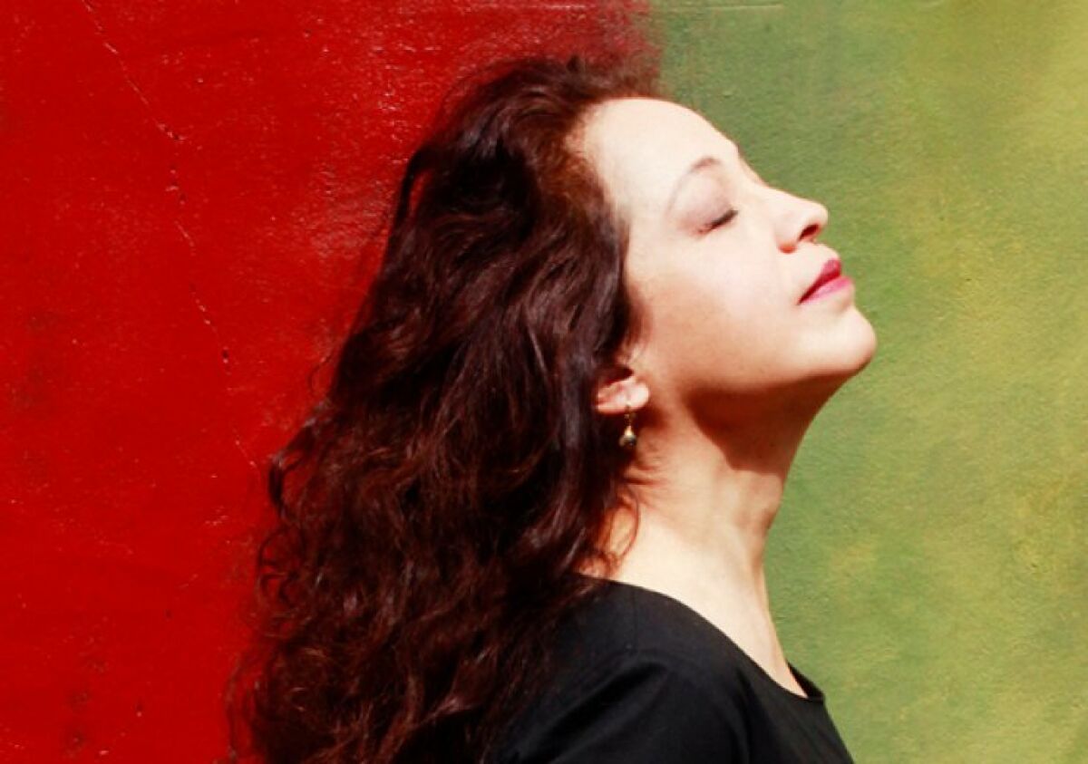 A photo of Perla Batalla in profile against a red and green background.
