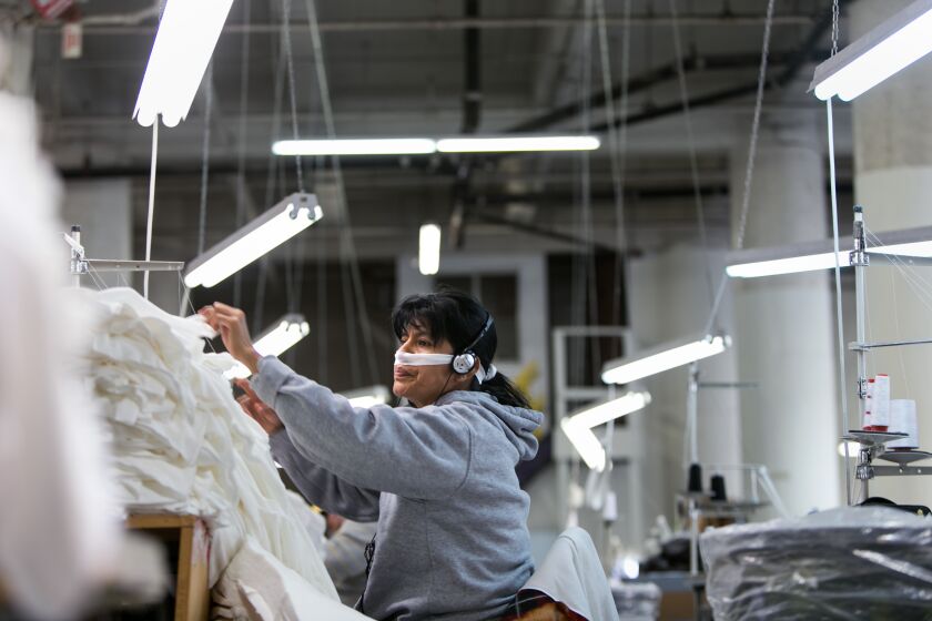 LOS ANGELES, CALIF. -- THURSDAY, JANUARY 22, 2015: A garment worker sorts out finished T-shirts in the sewing department at Groceries Apparel, a small garment factory in Los Angeles, Calif., on Jan. 22, 2015. (Marcus Yam / Los Angeles Times)