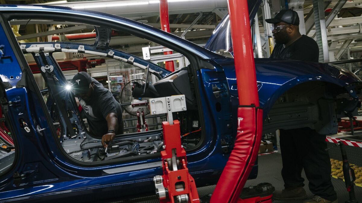 Damien Boozer and Paul Jacob work on the general assembly of a Model 3 at the Tesla factory in Fremont, Calif., on July 26.