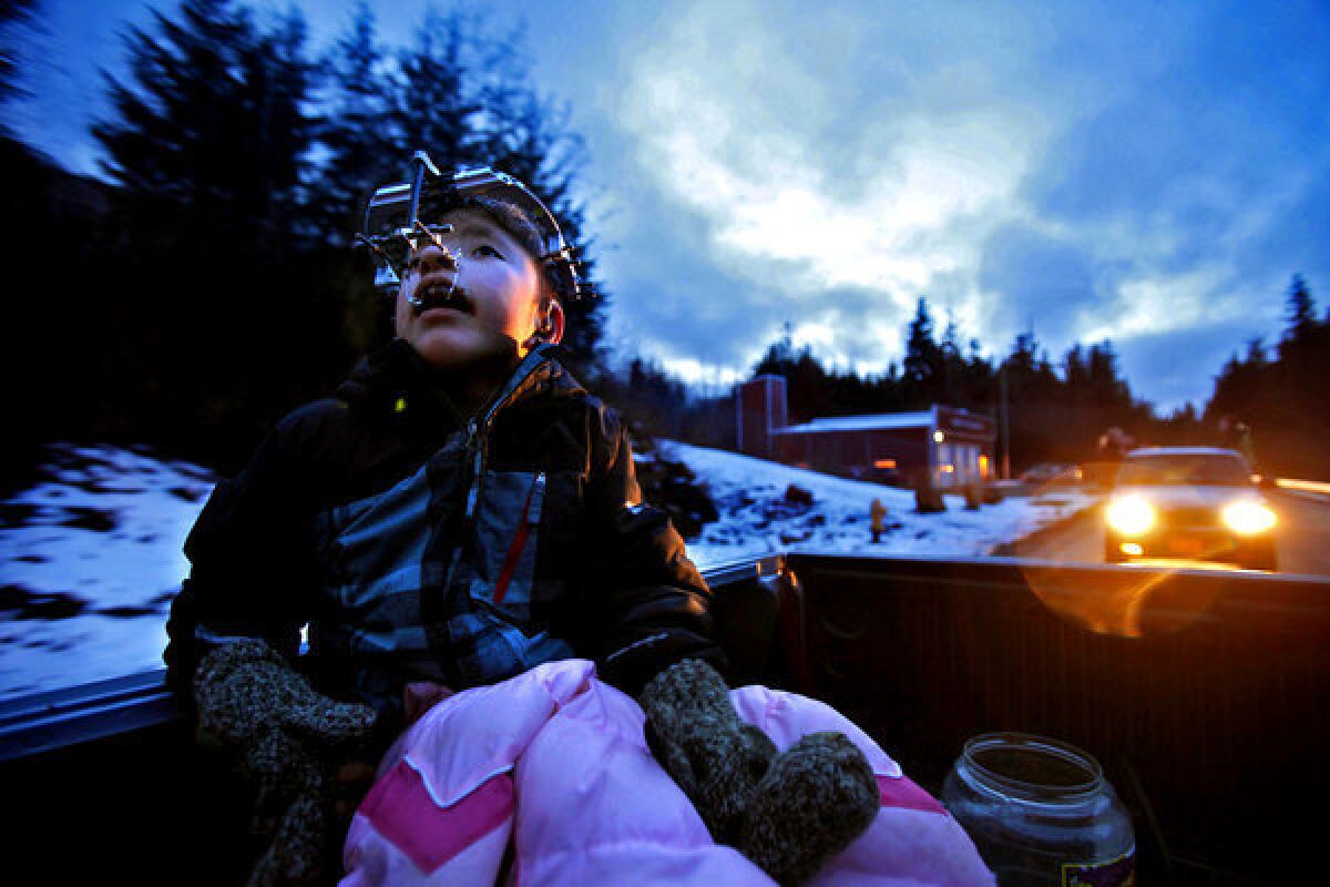James Weatherwax, 11, rides in the back of his grandfather's truck while participating in a celebratory parade through the town of Klawock, Alaska, honoring the Klawock High School basketball team, which won the state championship in March. He was born with Apert syndrome, a rare genetic mutation that fuses the skull prematurely, distorts the bones of the face and melds the muscles and bones of the fingers and toes. In late January 2013, an innovative metal brace, or halo, was attached to his head to help realign his face. He has undergone more than a dozen operations at Children's Hospital in Seattle to correct the appearance of his face and hands.