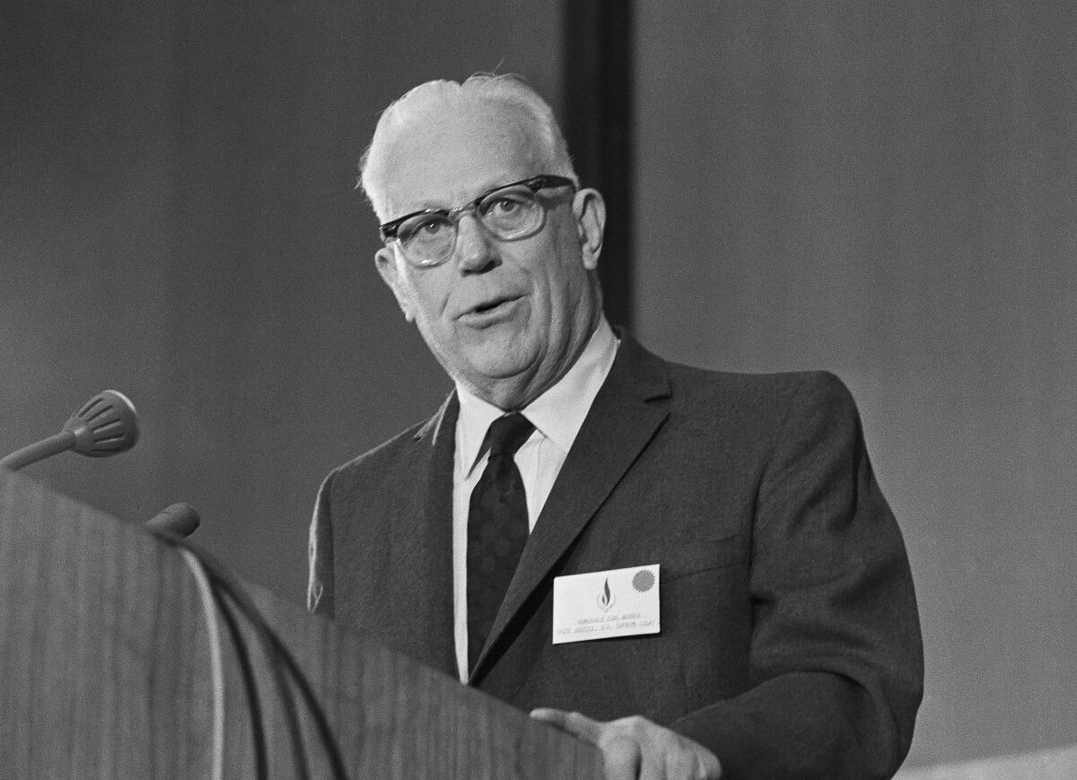 A black and white photo of Earl Warren at a lectern
