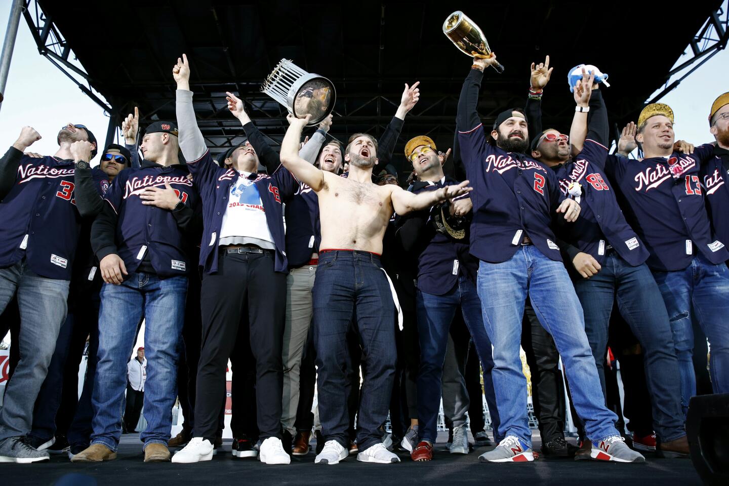 Washington Nationals second baseman Brian Dozier, center, holds up the World Series trophy as he celebrates with teammates at a rally after a parade to celebrate the team's World Series baseball championship over the Houston Astros, Saturday, Nov. 2, 2019, in Washington. (AP Photo/Patrick Semansky)