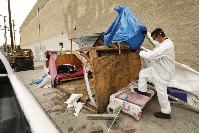 LOS ANGELES, CA - MAY 23, 2019 - Jesus Sanchez, left, and Javier Villarreal, right, with Watershed Protection Division of Los Angeles Bureau of Sanitation first secure the scene of hazardous materials as crews arrive to clean up the homeless encampment of Rickey Harris at 41st Place and Alameda on May 23, 2019 that has received complaints. There has been a uptick in complaints about homeless encampments that are filed through 311 over the last couple of years. They have gone up 166%. (Al Seib / Los Angeles Times)