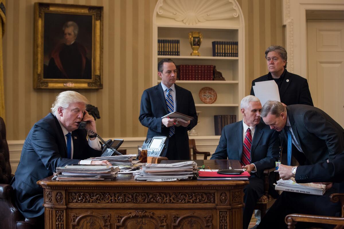 President Donald Trump speaks on the phone with Russian President Vladimir Putin in the Oval Office of the White House on January 28, 2017. Also pictured, from left, White House Chief of Staff Reince Priebus, Vice President Mike Pence, White House Chief Strategist Steve Bannon, and Press Secretary Sean Spicer.